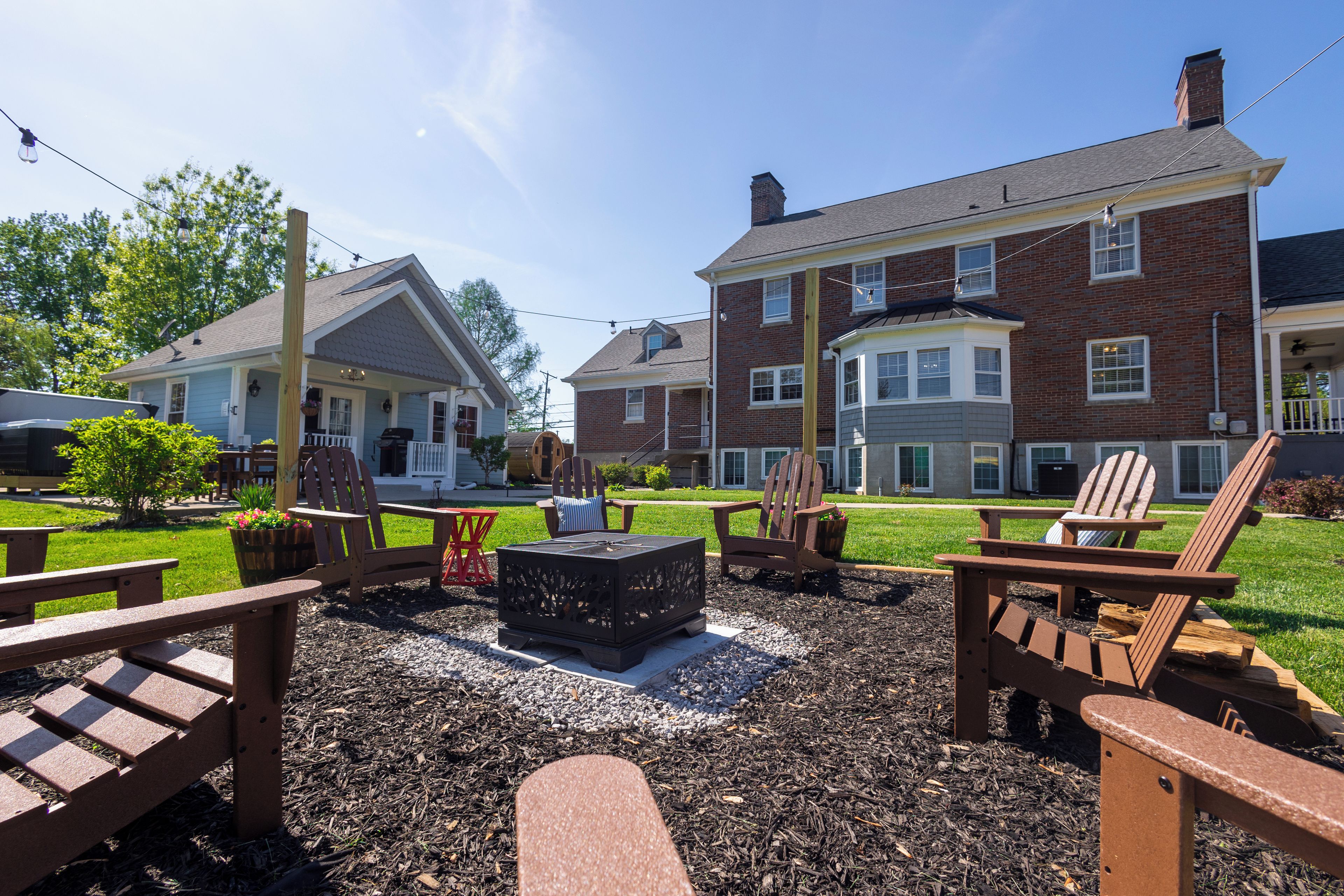 A patio area with Adirondack chairs, a fire pit, and a well-maintained lawn.
