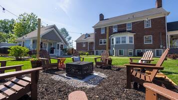 A patio area with Adirondack chairs, a fire pit, and a well-maintained lawn.