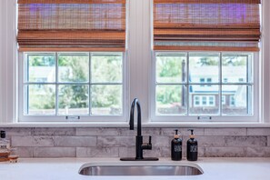 A kitchen with a stainless steel sink, two bottles labeled 'HAND' and 'DISHES', and a bottle of whiskey.