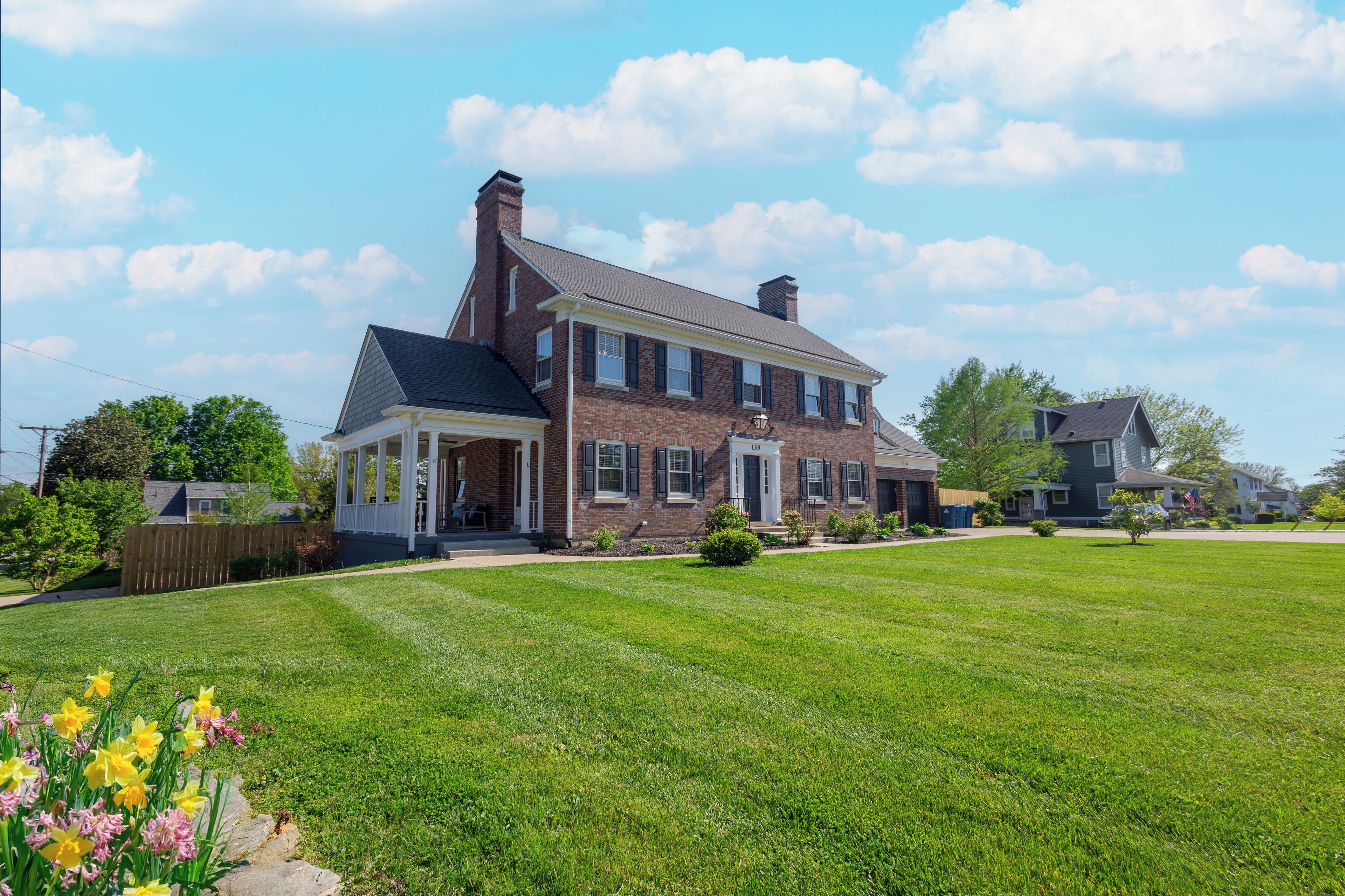A two-story brick house with a front porch and a well-maintained lawn.