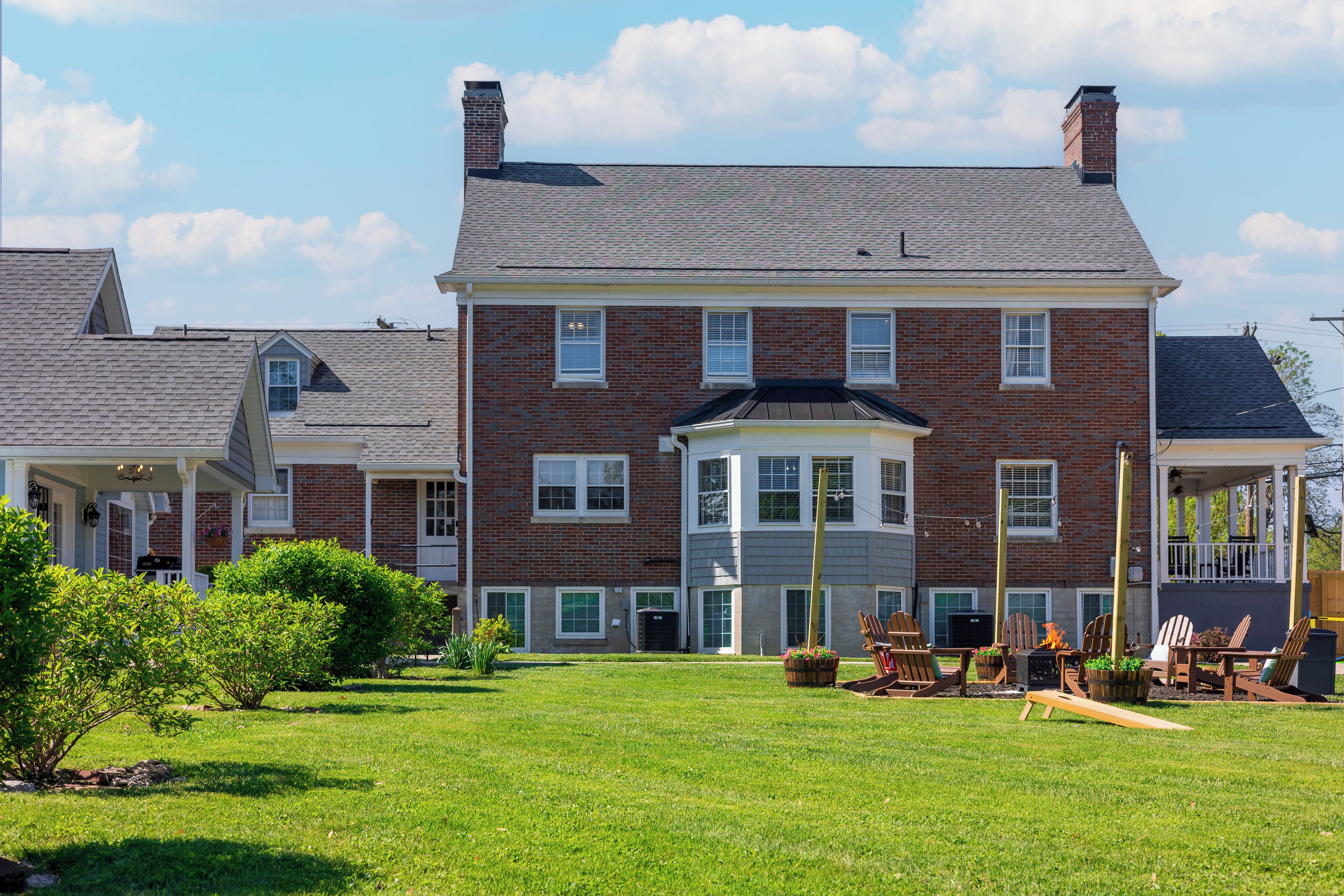 A large brick house with a front porch, a garage, and a well-maintained lawn.