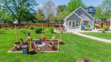 A backyard with a fire pit, wooden chairs, and a small shed.