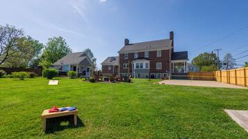 A residential property with a well-maintained lawn, a patio area with outdoor furniture, and a large brick house with multiple windows.