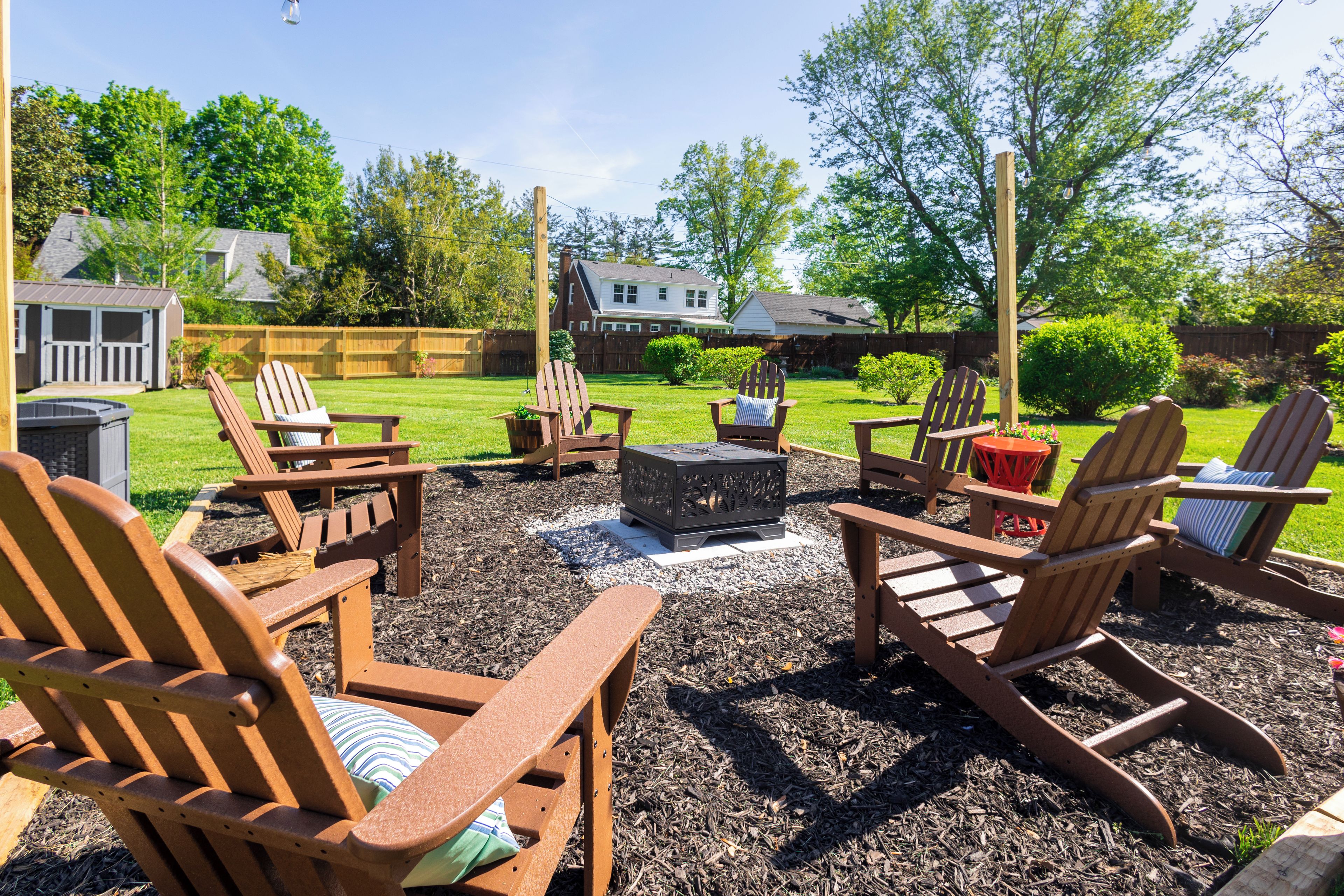 An outdoor seating area with Adirondack chairs and a fire pit.