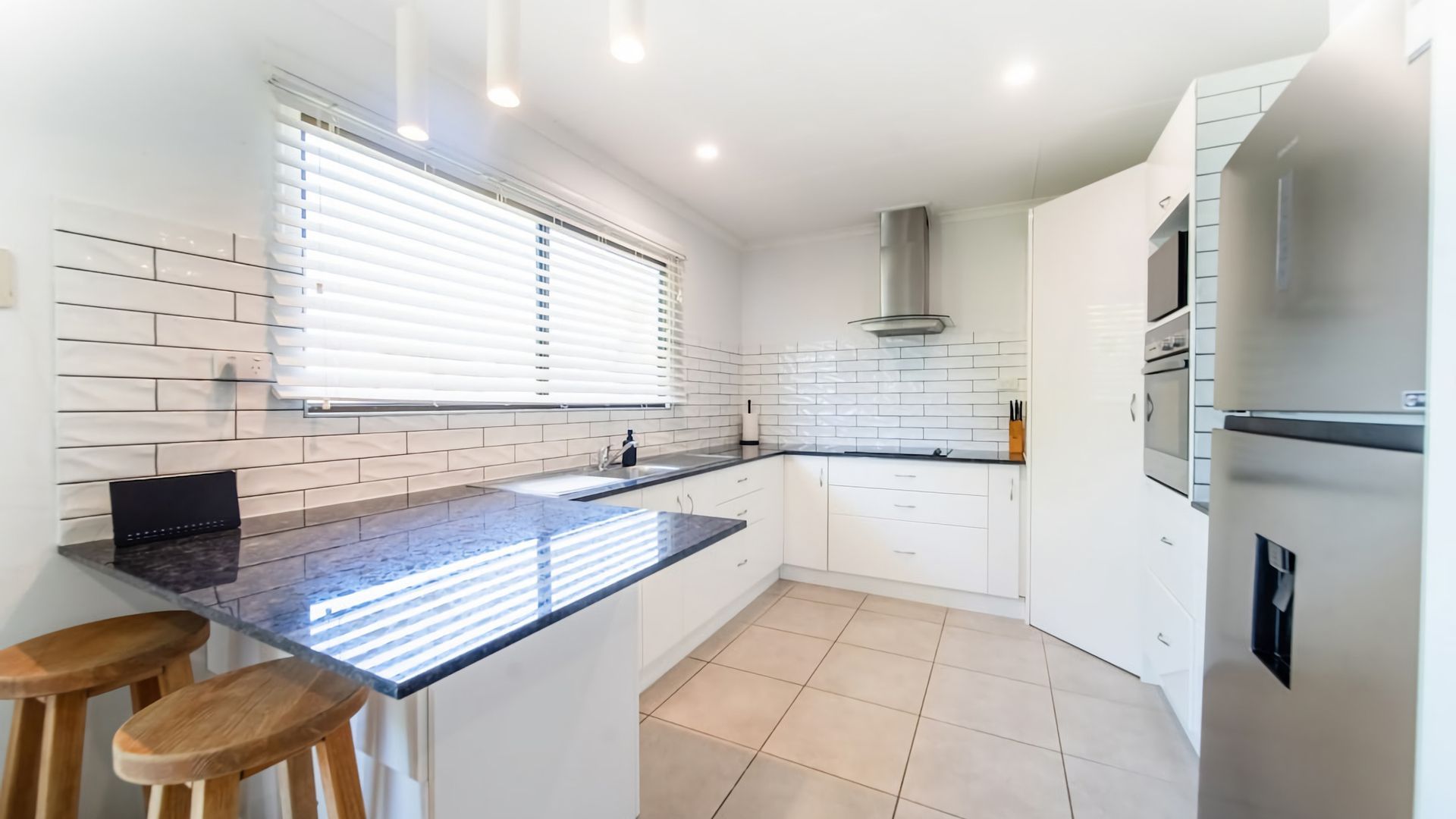 Una cocina moderna con una isla central, armarios blancos y un horno empotrado.