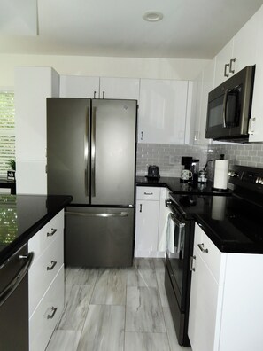 A modern kitchen with stainless steel appliances, white cabinetry, and a black countertop. - Linen and Palm 1bed/1bath heart of Fort Lauderdale (Fort Lauderdale)