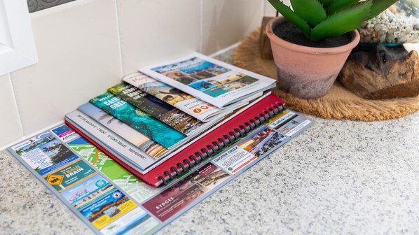 A collection of travel brochures and a red spiral notebook on a countertop.