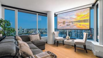 A modern living room with a large window, a sofa, two chairs, and a small table.