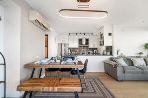 Eine moderne Küche mit weißen Schränken, einer zentralen Kochinsel und einem Essbereich mit Holztisch und Stühlen.