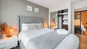Une chambre moderne avec un grand lit, des tables de chevet, une armoire et un miroir.