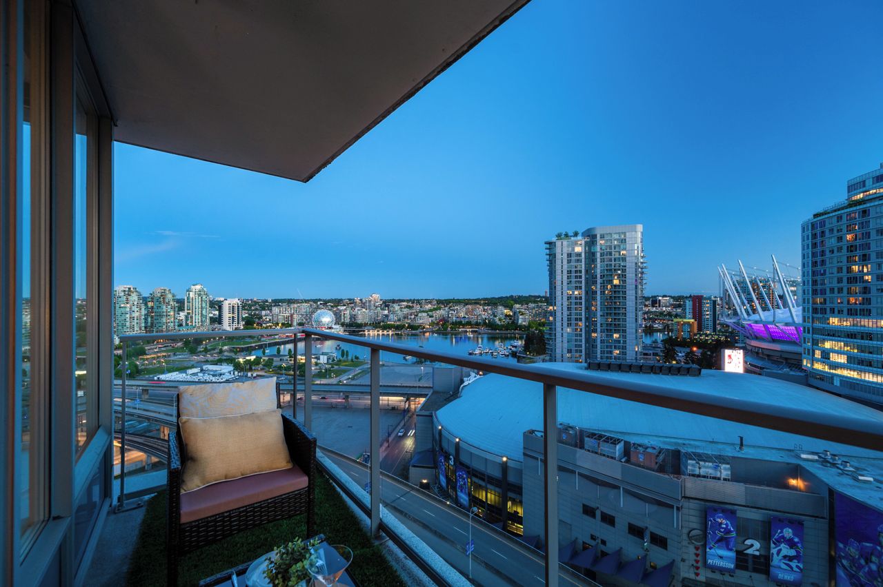 A balcony with a view of a cityscape, including high-rise buildings and a bridge.