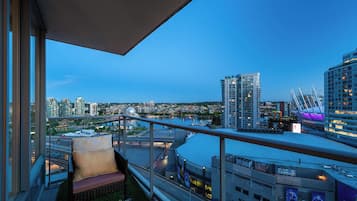 A balcony with a view of a cityscape, including high-rise buildings and a bridge.
