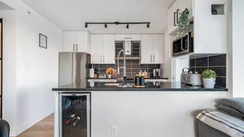 A modern kitchen with white cabinets, a black countertop, and a built-in microwave.