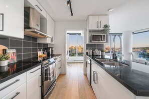 Une cuisine moderne avec un plan de travail noir, des appareils en acier inoxydable et une vue sur la ville.