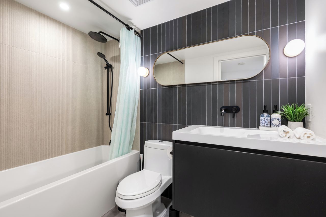 A modern bathroom with a bathtub, toilet, and a large mirror.