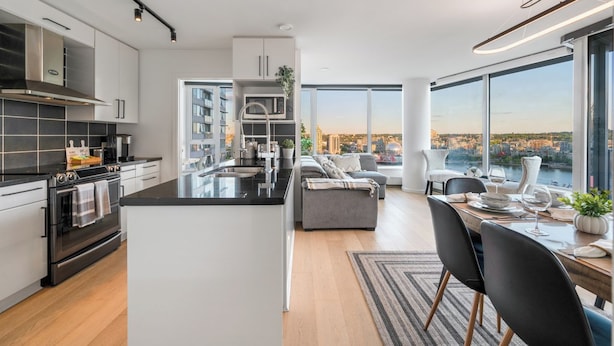 Une cuisine moderne dotée d’un îlot central, un coin repas offrant une vue agréable et un espace de vie avec un canapé et des fauteuils.