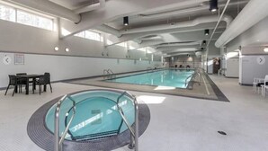 Une piscine intérieure avec des couloirs de nage bien délimités, un espace détente avec des tables et une grande fenêtre laissant entrer la lumière naturelle.