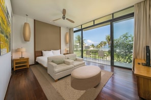 A modern hotel room with a large bed, a sofa, a round ottoman, a ceiling fan, and a balcony with a view of palm trees. - Koaniva Hyatt Regency Da Nang Resort (Da Nang)