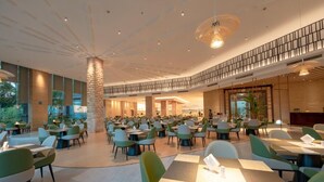 A spacious indoor dining area with multiple tables and chairs, a central pillar, and a mezzanine level with a railing. - Chensheng International Hotel (Zhangjiajie)