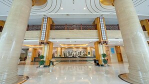 A lobby with marble columns, a reception desk, and a decorative wall. - Chensheng International Hotel (Zhangjiajie)