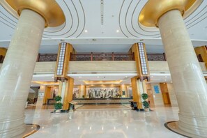 A lobby with marble columns, a reception desk, and a decorative wall. - Chensheng International Hotel (Zhangjiajie)
