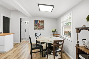 A dining area with a round table, four chairs, and a ceiling light fixture. - Cedar Lake Sunrise: 1BR, 1.5 Bath with Lake View and Back Porch (Cedar Lake)