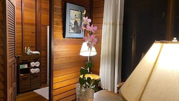 A wooden interior with a lamp, a vase with flowers, and a framed picture on the wall.