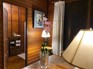 A wooden interior with a lamp, a vase with flowers, and a framed picture on the wall. - the NOW by Kru Se Mini Villa (Mae Rim)