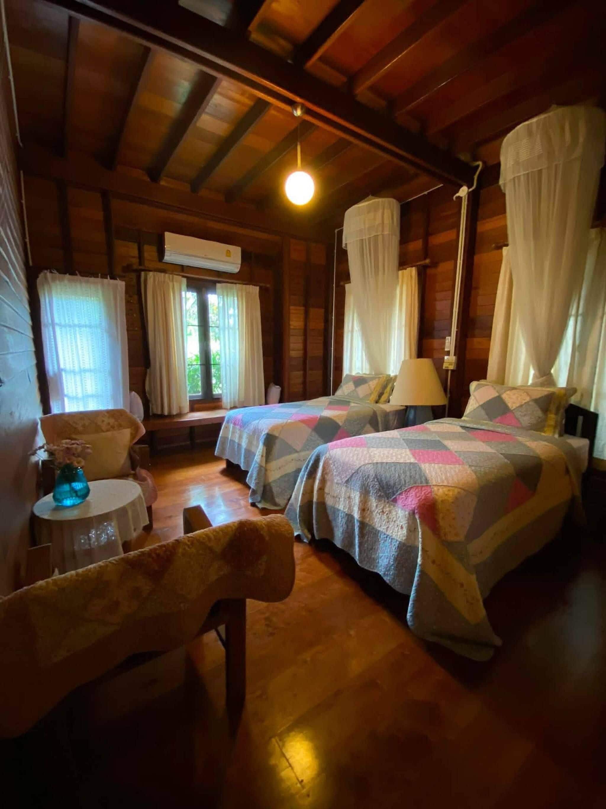 A wooden cabin with two beds, a small table, and a chair.