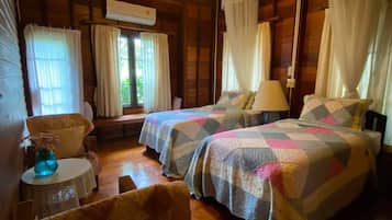 A wooden cabin with two beds, a small table, and a chair.