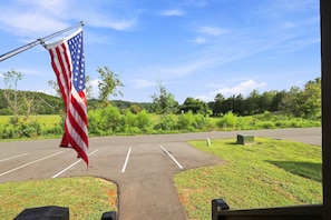 Ein Parkplatz mit Fahnenmast und amerikanischer Flagge, umgeben von Grünflächen und blauem Himmel.