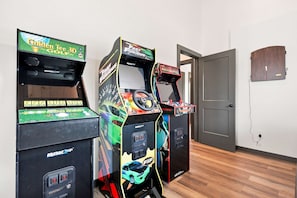 Drei Spielautomaten in einem Raum mit Holzboden und einer Tür im Hintergrund.