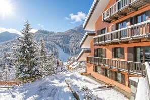 Ein Hotel mit Blick auf die Berge, schneebedeckte Bäume und einem klaren Himmel.