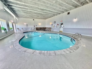 Une piscine intérieure à bords incurvés, dotée d’une échelle en métal et d’un sol carrelé.