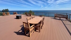 Een houten terras met een ronde tafel en stoelen, met uitzicht op een waterpartij.