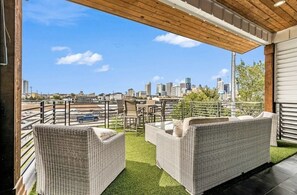 A rooftop terrace with wicker furniture, a view of a city skyline, and a clear sky. - Modern/Luxury/Rooftop Deck/Downtown/Heated Pool/5BDRM (Houston)