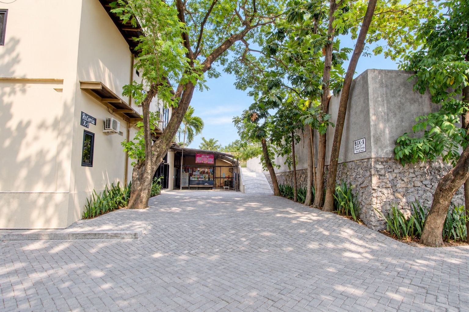 Un sendero pavimentado que conduce a un edificio con un letrero que indica un negocio.