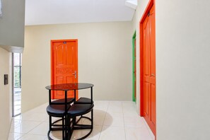 A hallway with a glass-top table and two chairs, a door labeled '101', and a green door. - Hotel O near Ahmad Yani International  (Semarang)