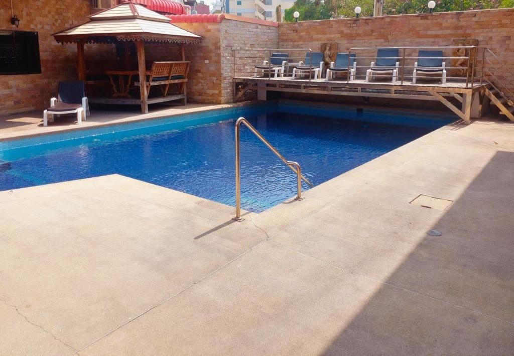 A swimming pool with a sunshade, lounge chairs, and a small table.