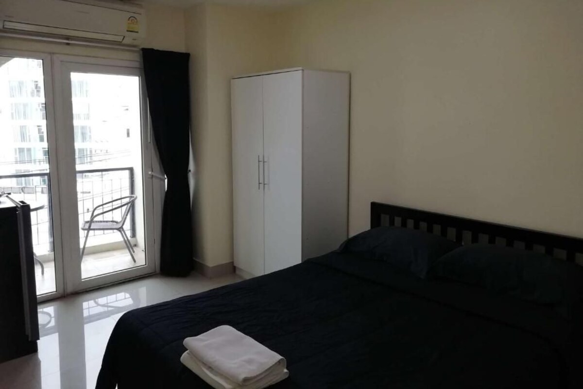 Ein Schlafzimmer mit einem Bett, einem Kleiderschrank und einer Schiebetür zum Balkon.