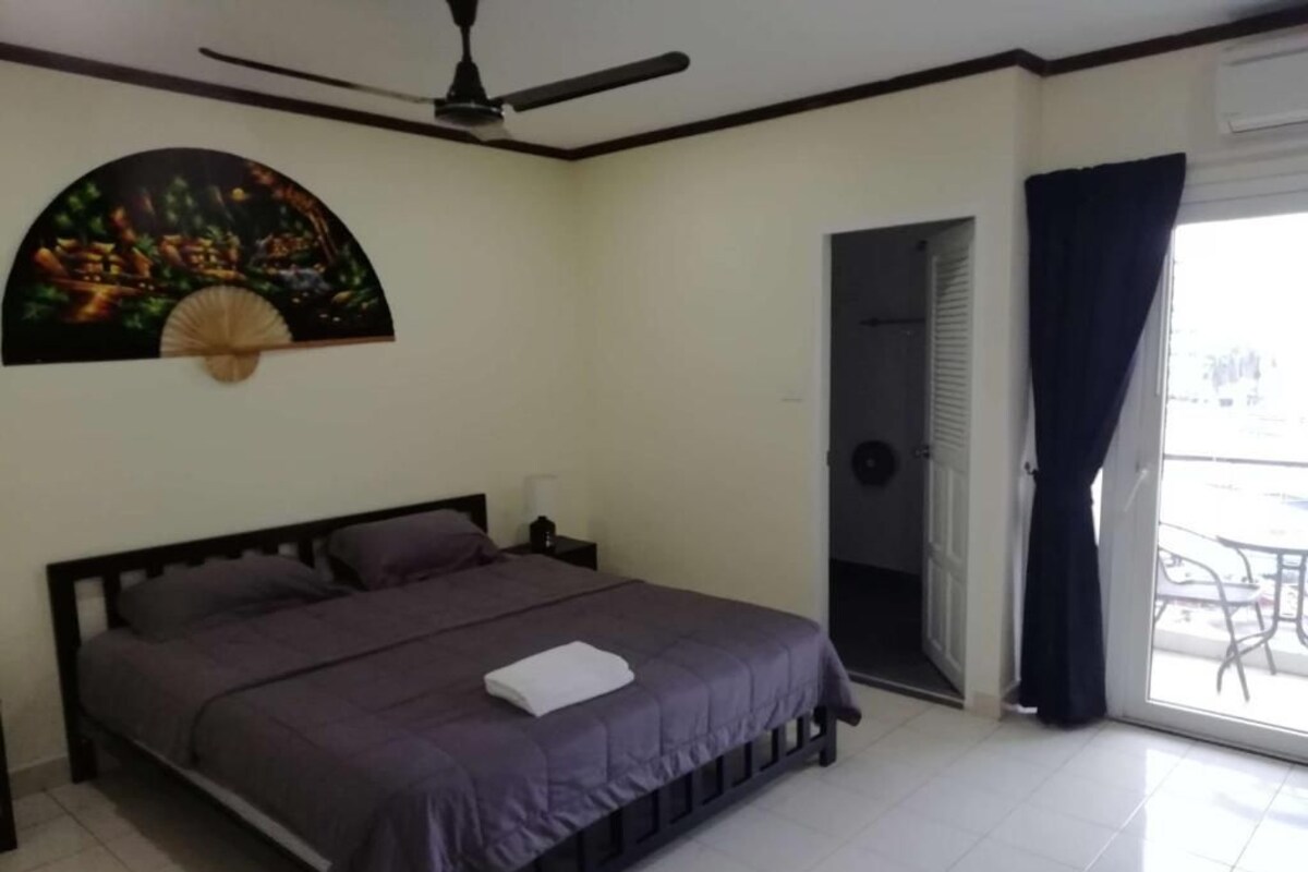 Ein Schlafzimmer mit einem Bett, einem Deckenventilator, einer Tür, die auf einen Balkon führt, und einem Wandbild.