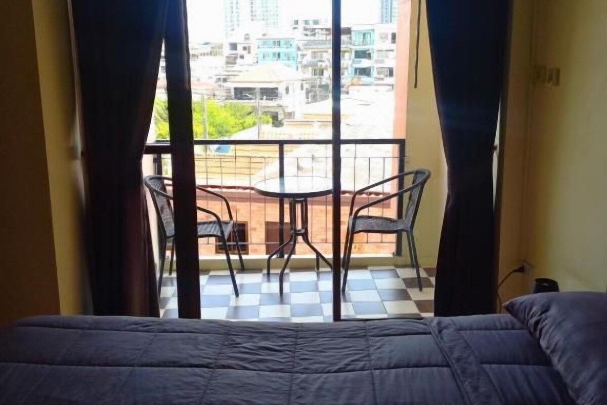 Ein Hotelzimmer mit Bett, einem Balkon mit Stühlen und Blick auf die Stadt.