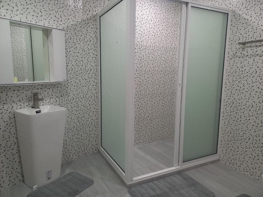 A bathroom with a shower enclosure, a sink, and a mirror.
