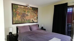 A bedroom with a bed, two bedside tables, a wall-mounted artwork, and a window with curtains. - Dania Pattaya (Pattaya)