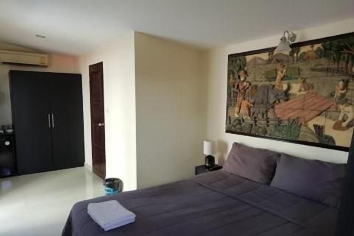 Ein Schlafzimmer mit einem Bett, einem Nachttisch, einem Gemälde und einem Kleiderschrank.