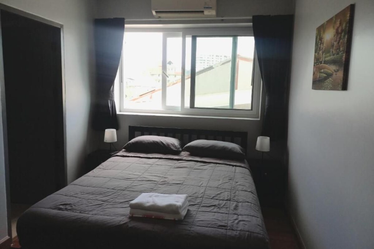 Ein Schlafzimmer mit einem Bett, einem Fenster, einer Klimaanlage und einem Gemälde an der Wand.