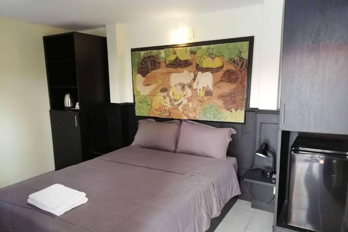 Ein Schlafzimmer mit Bett, einem Bild darüber, einem Kleiderschrank und einer Küchenzeile.