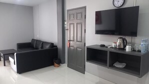 A modern living room with a sofa, a television mounted on the wall, and a door. - Dania Pattaya (Pattaya)