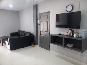 Ein modernes Wohnzimmer mit einer Couch, einem an der Wand montierten Fernseher und einer Tür.