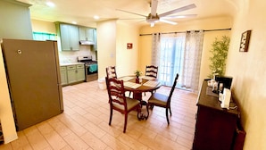 A compact kitchen with a dining area, a ceiling fan, and a view to the outside.